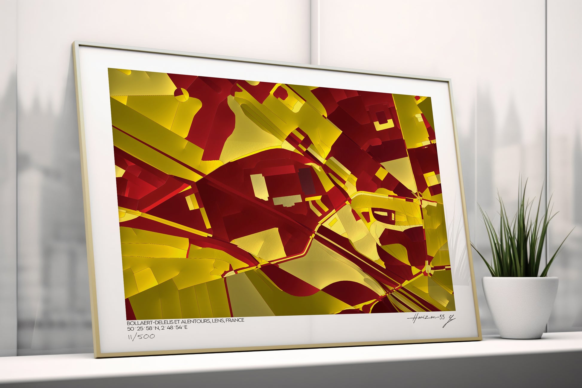 Affiche d’art imprimée représentant une carte abstraite du stade Bollaert-Delelis à Lens, France, dominée par des nuances rouges et jaunes, posée contre un mur à côté d’une plante décorative.