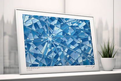 Tirage d’art des Champs-Élysées en carte abstraite bleue, posé contre un mur clair près d’une plante, lumière douce.