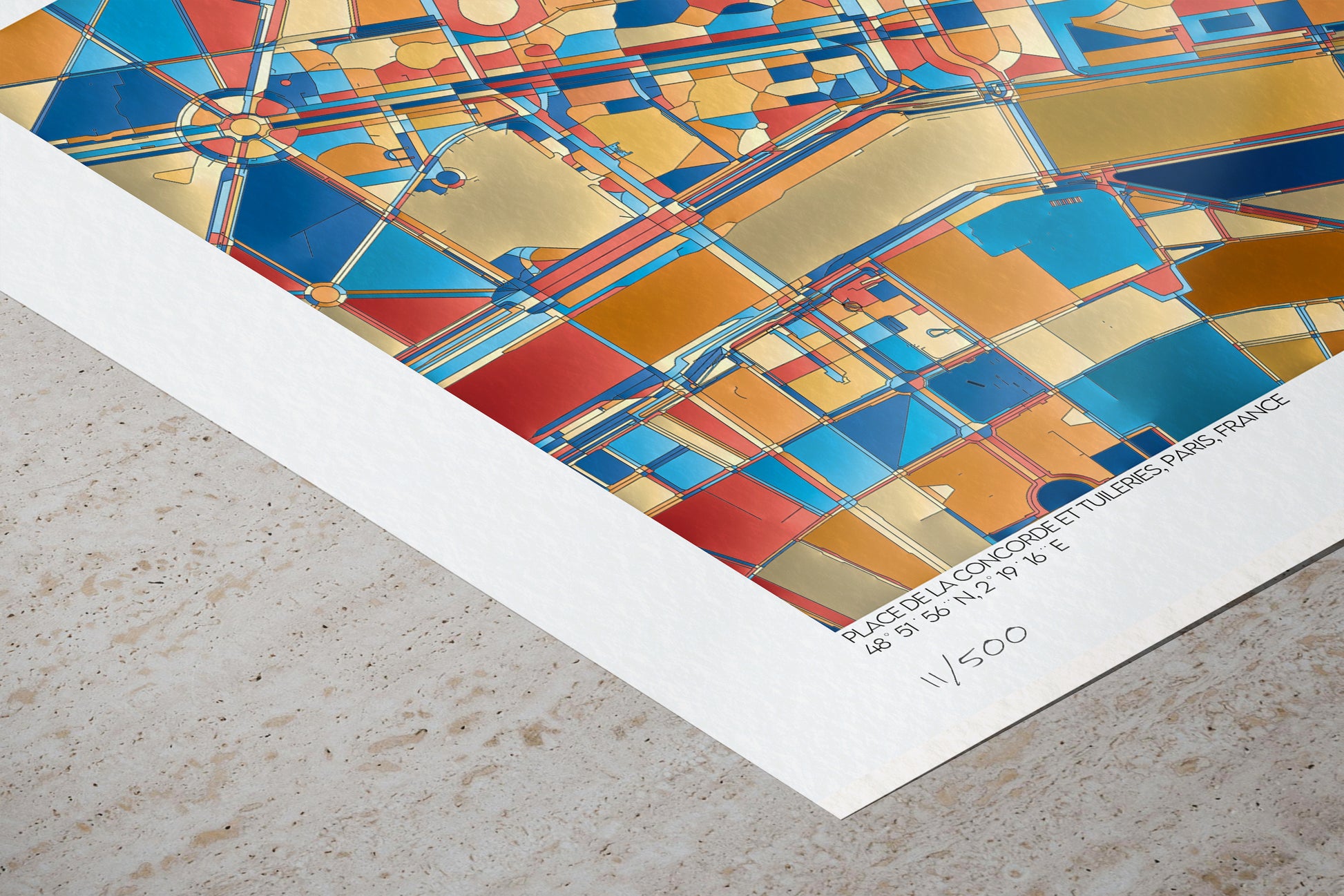 Détail du tirage numéroté de l’œuvre abstraite représentant la Place de la Concorde et le Jardin des Tuileries. On distingue la texture du papier, les motifs géométriques colorés et les coordonnées GPS imprimées en bas de l’affiche.