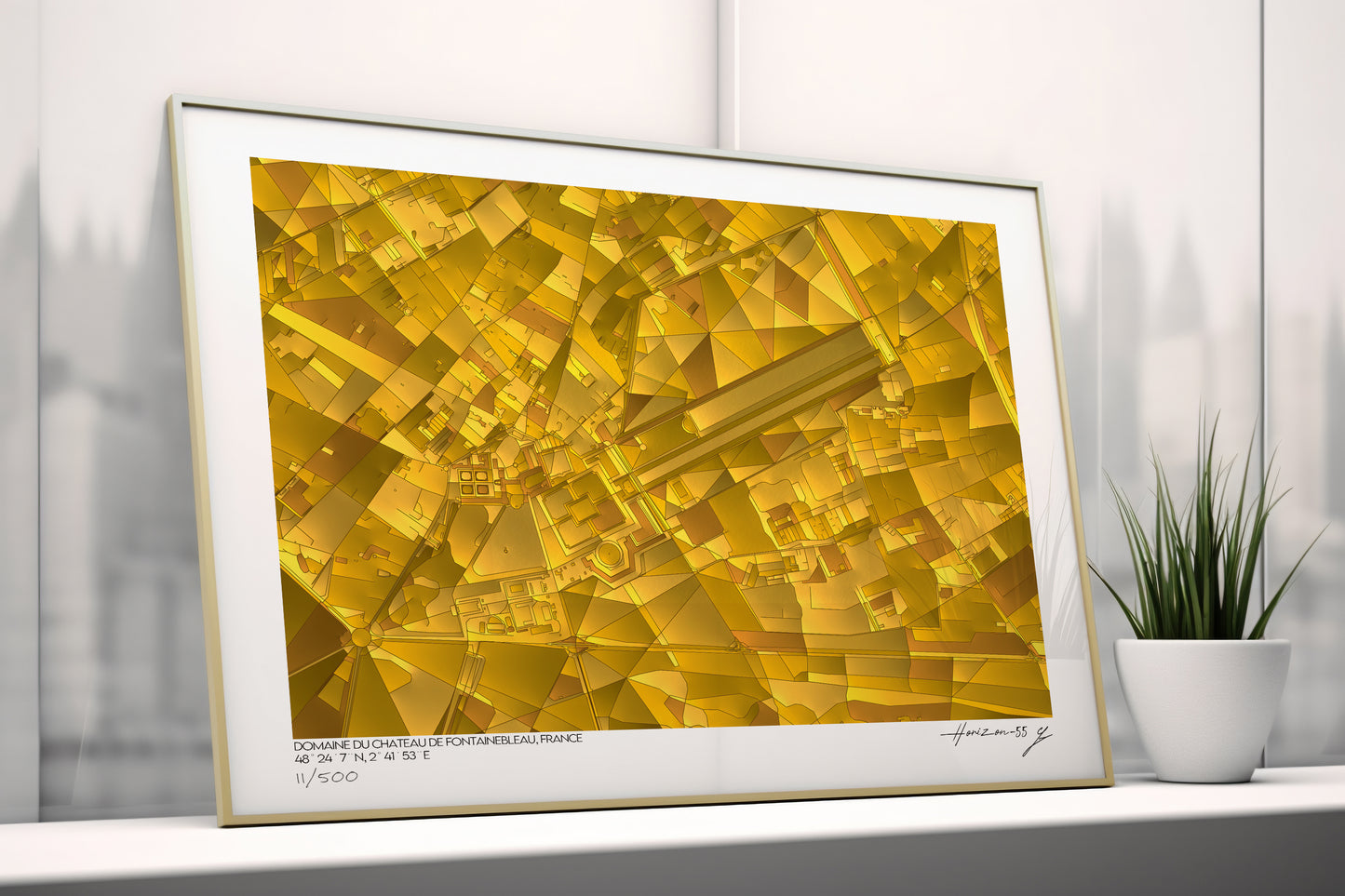Affiche cartographique abstraite de Fontainebleau aux teintes dorées, posée contre un mur blanc près d’une plante, lumière douce.