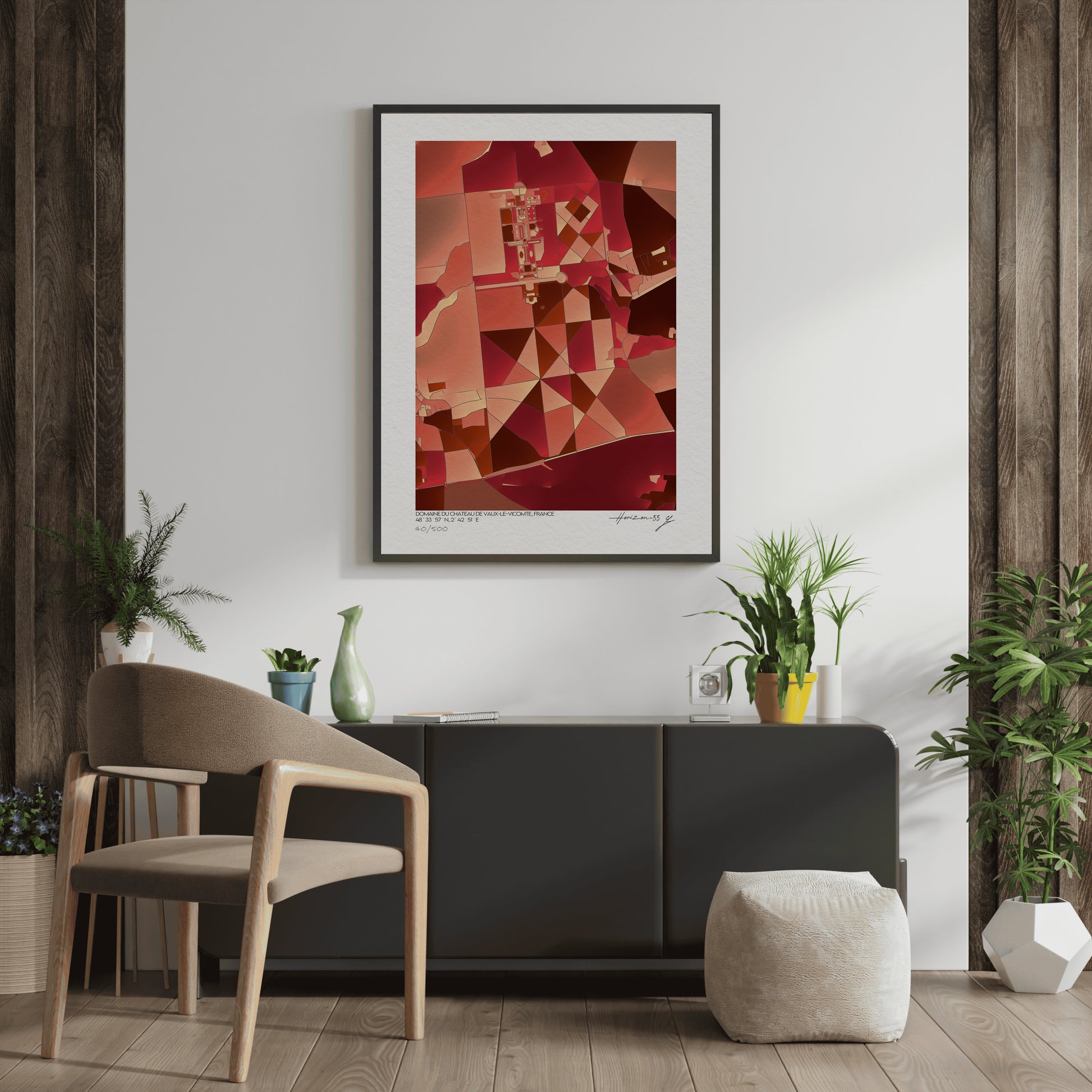 Affiche fine art représentant une carte géographique abstraite du domaine de Vaux-le-Vicomte, dominée par des nuances rouges et ocres, encadrée et exposée dans un intérieur élégant avec plantes vertes et mobilier contemporain.